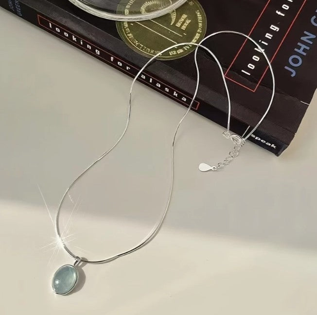 Collar Ovalado celeste fondo blanco y libro