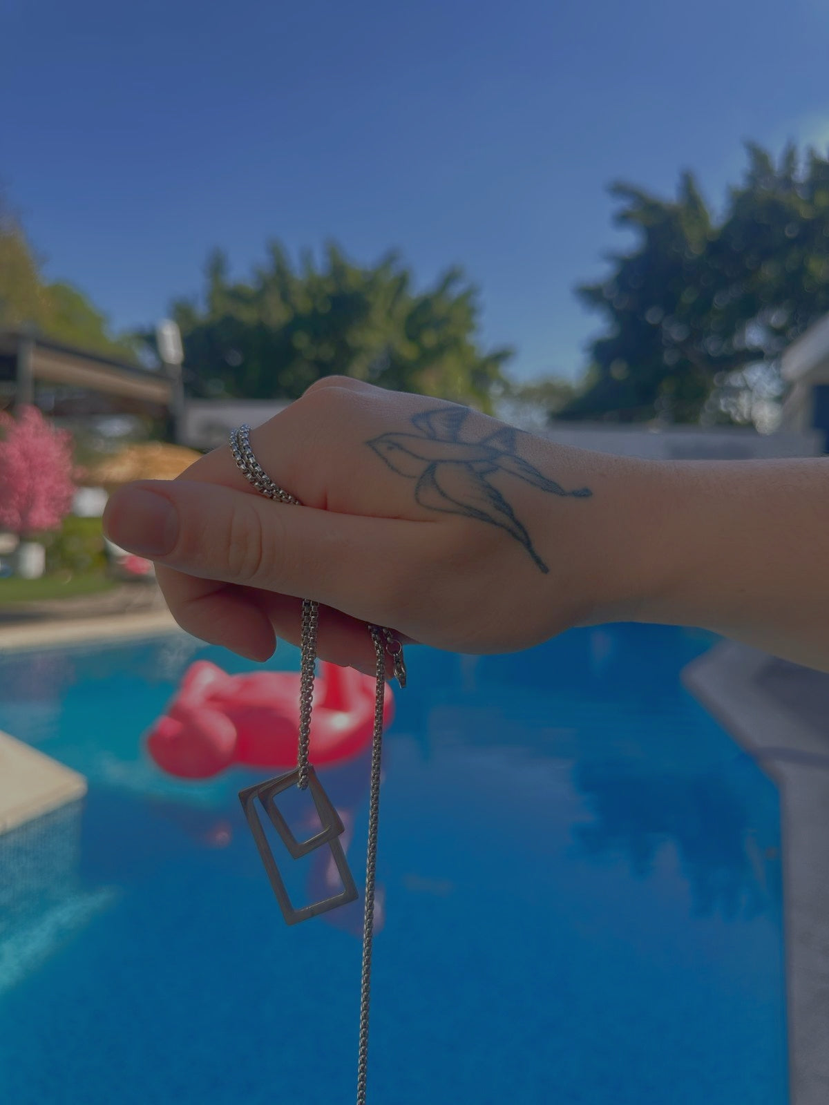 Mano con tatuaje de golondrina sosteniendo un collar muy estetico para hombre