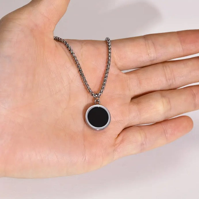 Mano sosteniendo cadena con pendiente circular negro Collar para hombre en El Salvador Collares Classic