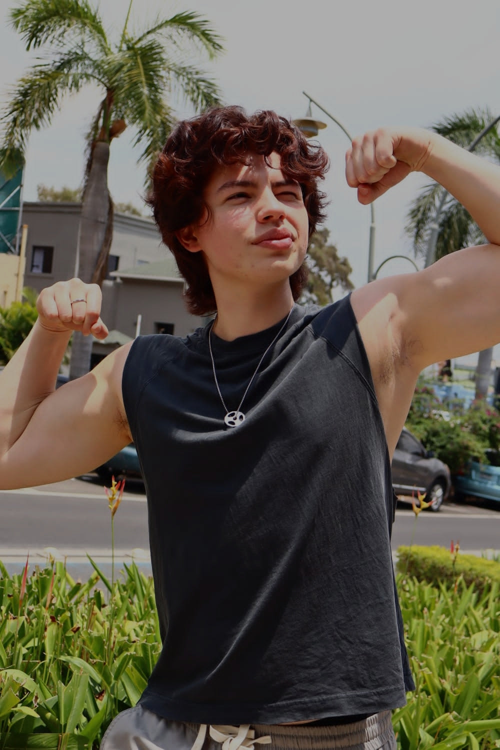 modelo flexeando bixeps mientras modela una cadena con disco de peso de gimnasio